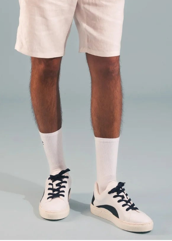Man wearing a white t-shirt and beige shorts against a plain background