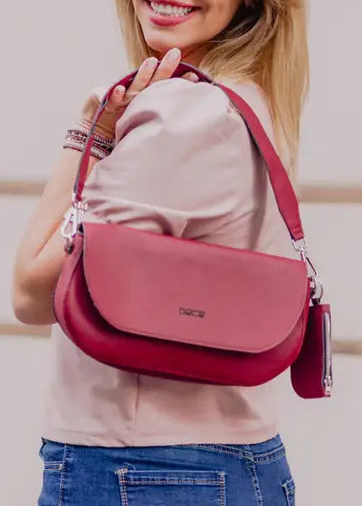 Woman holding a burgundy red handbag against a light background. plant based garnet colored leather bad made from apple peels.  Classic shoulder bag with fold-over design
